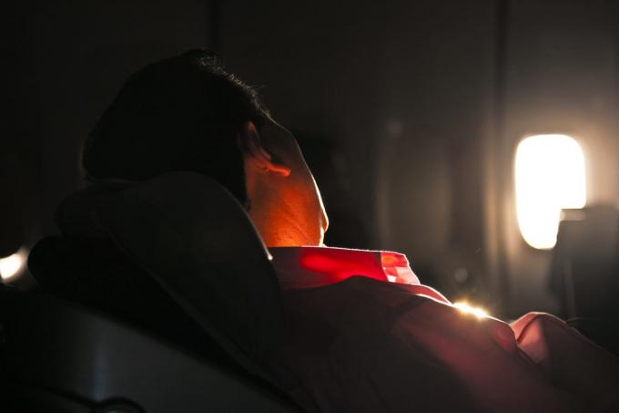 muž spí v sedadle lietadla za svitania